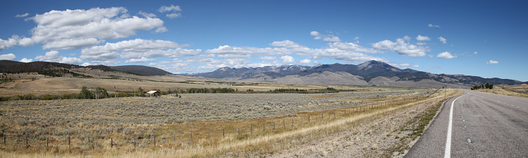True wide panorama of the Big Hole Valley in Montana, taken on a summer day, with numerous white clouds in the big blue Montana sky.