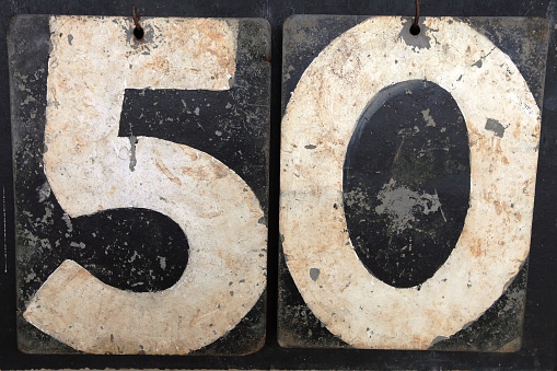 A photo of the number fifty (50) made from the numbers on an old cricket scoreboard.  The numbers are white and the back boards are black.  