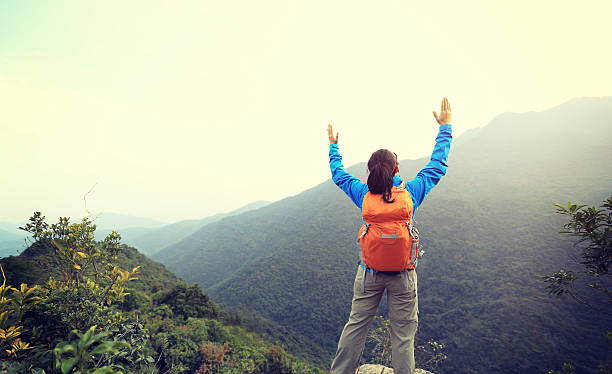 istock cheering woman hiker open arms at mountain peak 506296708