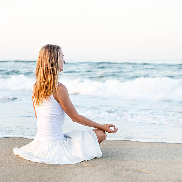 mujer meditando en el mar - equanimity fotografías e imágenes de stock