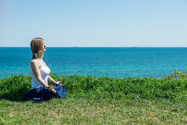 donna meditare al mare - equanimity foto e immagini stock