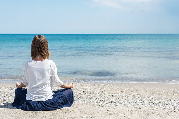 istock Woman meditating at the sea 506299702