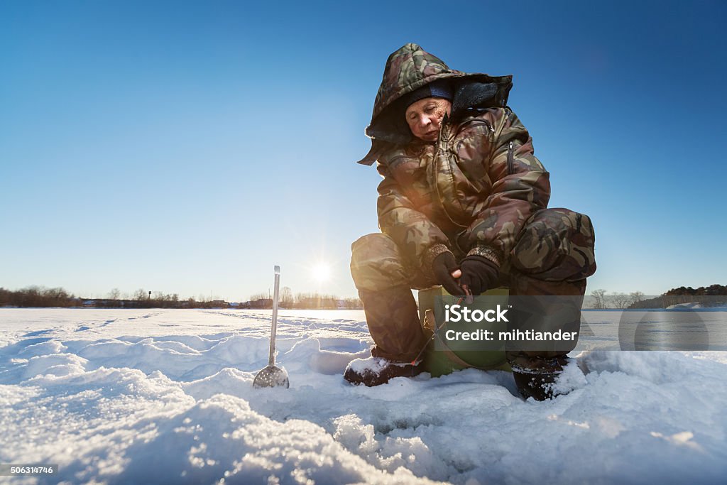 Fisherman on a winter lake Fisherman on a lake at winter sunny day Ice Fishing Stock Photo