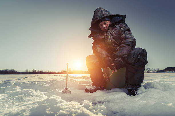 Fisherman on a winter lake Fisherman on a lake at winter sunny day man ice fishing stock pictures, royalty-free photos & images