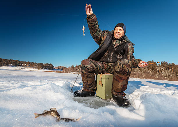 Fisherman on a winter lake Fisherman on a lake at winter sunny day man ice fishing stock pictures, royalty-free photos & images