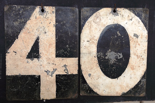 A digital photograph of the number forty(40) made up from the numbers of an old cricket scoreboard. The numbers are white and the back boards are black.