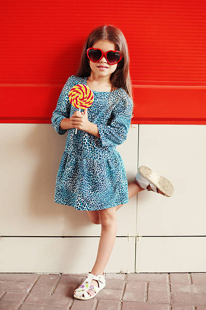 美しい小さな女の子お子様には、ペロペロキャンディ着用 dress 、レオパード - women sunglasses little girls glamour ストックフォトと画像