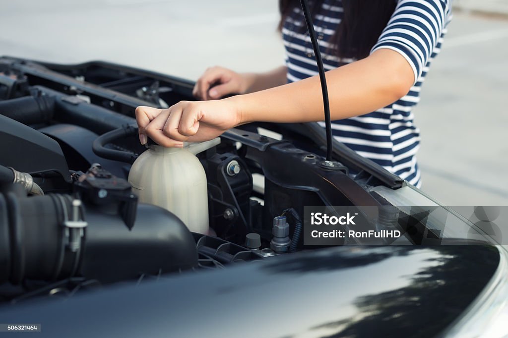 Checking Women checking coolant level of car. Car Stock Photo