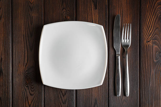 istock Empty plate, fork and knife on the dark wood background 506323152