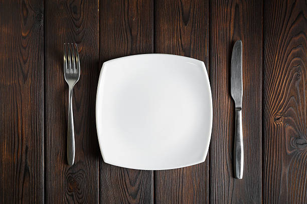 istock Empty plate, fork and knife on dark wood background 506323284