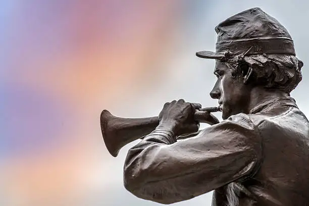 Bronze Profile Statue of Civil War soldier playing the bugle against colorful sky.