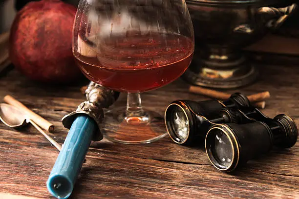 Photo of glass of cognac with binoculars and blue stained-glass candle