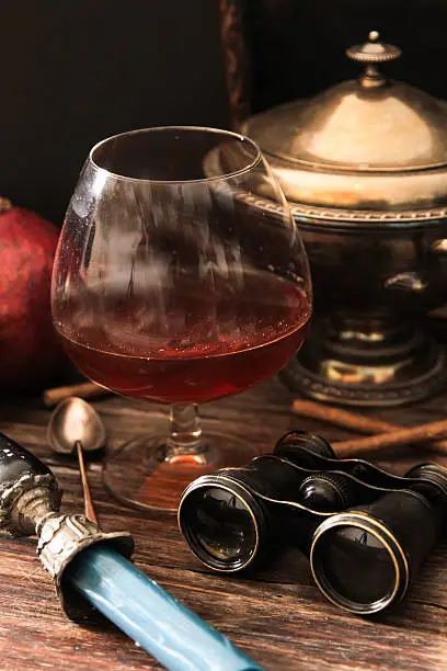 Photo of glass of cognac with binoculars and blue stained-glass candle