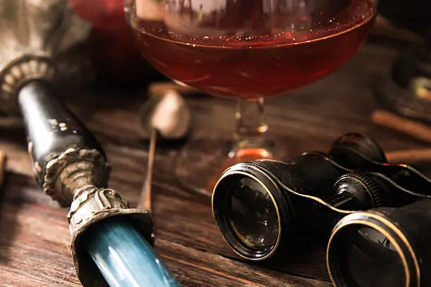 Photo of glass of cognac with binoculars and blue stained-glass candle