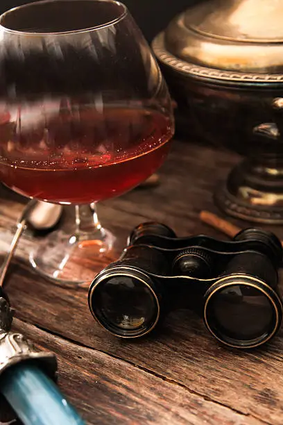 Photo of glass of cognac with binoculars and blue stained-glass candle