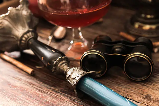 Photo of glass of cognac with binoculars and blue stained-glass candle