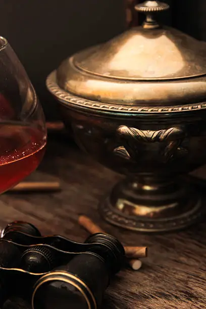 Photo of glass of cognac with binoculars and blue stained-glass candle