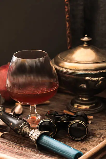 Photo of glass of cognac with binoculars and blue stained-glass candle