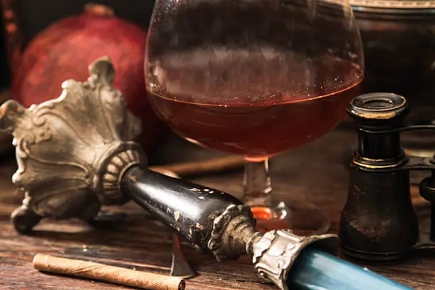 Photo of glass of cognac with binoculars and blue stained-glass candle