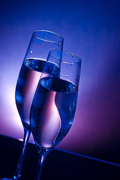 istock champagne flutes on bar table on blue and violet background 506342538