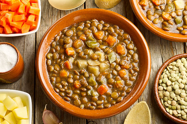 Vegetable lentil soup Vegetable lentil soup on a clay pot and admixtures on wooden table lentil stock pictures, royalty-free photos & images