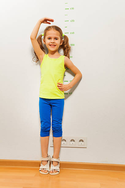 istock Cute girl checking height on wall with hand 506351522