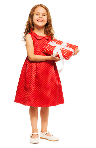 Front view of a cute little girl is holding a pink gift box in her hands with a nice smile in front of pure white background.
