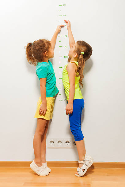 istock Two girls stretch up with hand on scale 506352230