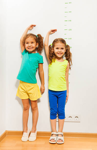 istock Two girls hold hands over hand near scale on wall 506352274