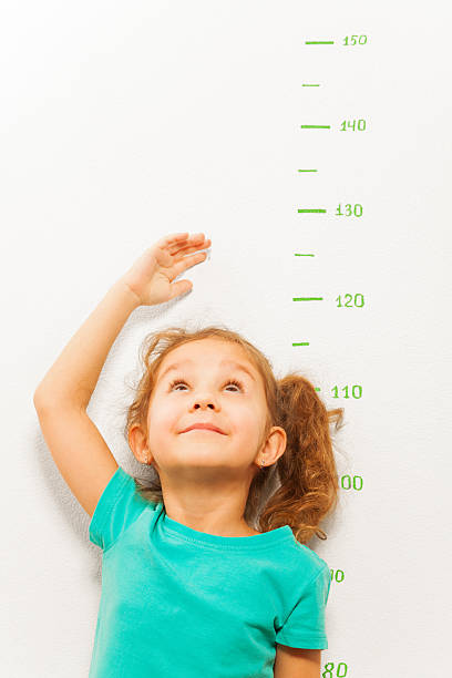 istock Girl measure height with hand looking up 506352876