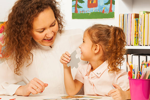 istock Teacher helping girl to assemble a jigsaw puzzle 506353746