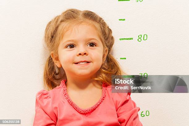 Little Girl Measuring Height Against Wall In Room Stock Photo - Download Image Now - Growth, Human Height, Ruler