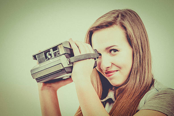 Woman holding retro photo camera with flash.