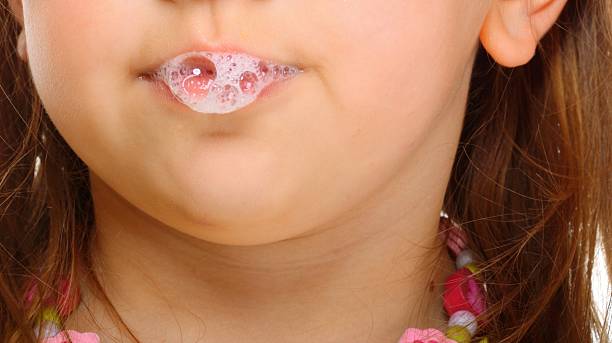 Close up little girl doing fun saliva bubbles stock photo