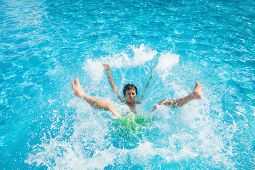 Man falling and splashing into water of swimming pool