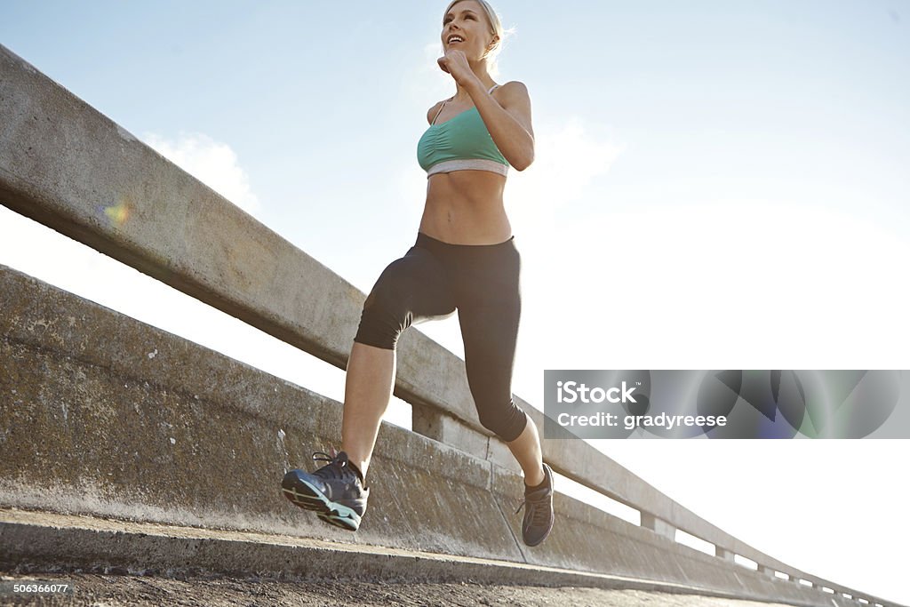 Racing the sun Low angle shot of an attractive young woman on a morning run 30-39 Years Stock Photo