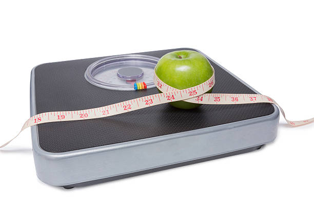 acercamiento de escala, cinta y manzana aislado sobre blanco - weight scale apple comparison balance fotografías e imágenes de stock