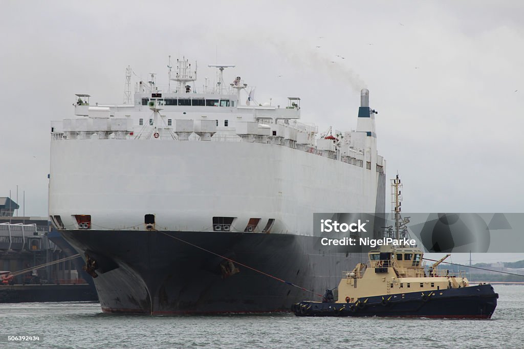 Large Ship with Tugboat Large Black and White Ship being manoeuvred in Port by Tugboat  A Helping Hand Stock Photo