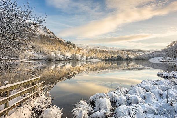 Rydal, Lake District in winter snow A beautiful still winter morning with a fresh covering of snow at Rydal Water in the Lake District UK, sunlight casting a glow upon the trees. english lake district photos stock pictures, royalty-free photos & images