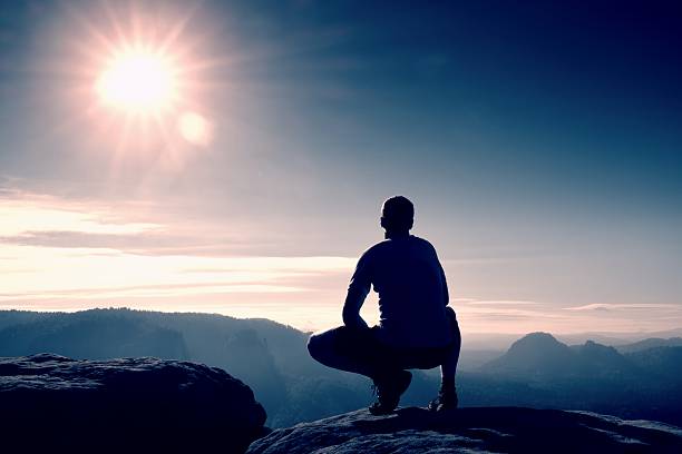 istock Man in black pants  on rock empire and watching over 506396984