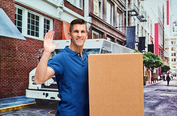 trabajador sonriente sosteniendo la caja y agitando la mano - correspondence waving horizontal outdoors fotografías e imágenes de stock