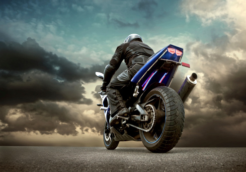 Hombre asiento en la motocicleta bajo cielo con nubes photo