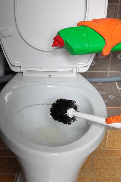 istock Gloved hand cleaning toilet bowl using brush 506400939