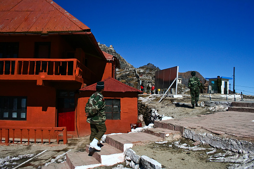 Nathi la, Sikkim, India - December 9, 2007: Taken this picture of the Nathu la pass Indo China border. In the picture from Indian side shows couple of Indian army soldiers approaching border fence where Chinese army soldiers are standing. In the background are the overlooking Chinese bunker positions and on laft side the red building used for flag meeting. 