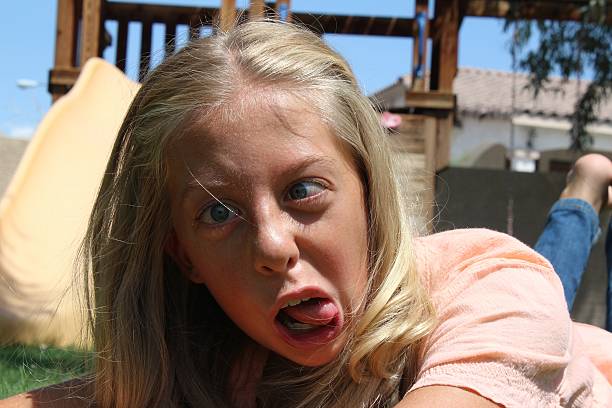 A surprised girl in a baseball cap is looking at the camera. A little girl with blond hair and brown eyes is surprised. Close-up portrait. great news.