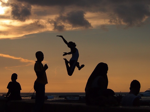 Stone Town, Zanzibar, Tanzania - November 25, 2015: Locals run and jump into the sea in Zanzibar as the sun sets.