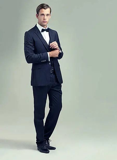 A full length studio shot of a handsome young man in a stylish vintage suit
