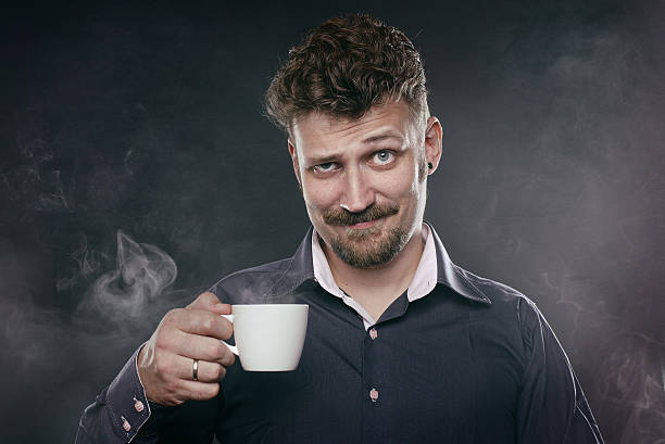 bonito barba homem de pé na neblina com uma xícara de café - men sex symbol sensuality human face - fotografias e filmes do acervo