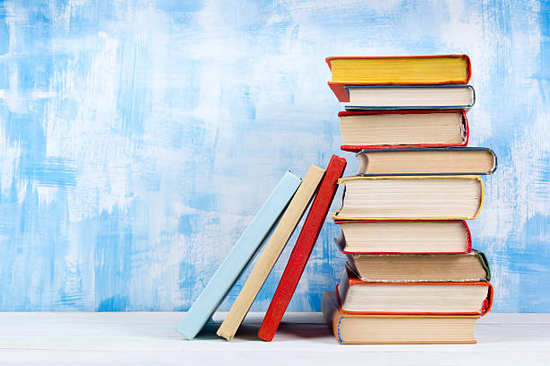 Stack of colorful hardback books, open book on blue background