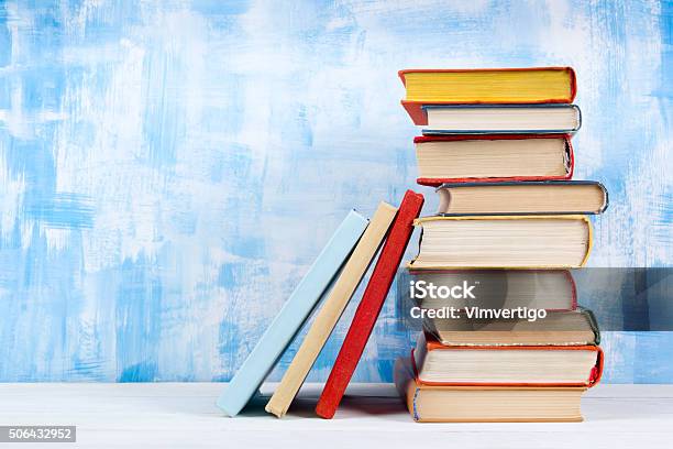 Stack Of Colorful Hardback Books Open Book On Blue Background Stock Photo - Download Image Now